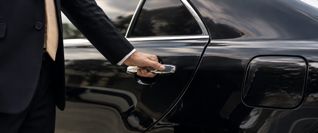 Chauffeur opening the door of a black car for an airport pickup in Seattle
